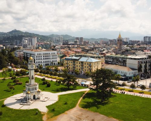 Aerial drone view of Batumi, Georgia. Old and modern buildings, greenery, roads, mountains, cloudy sky